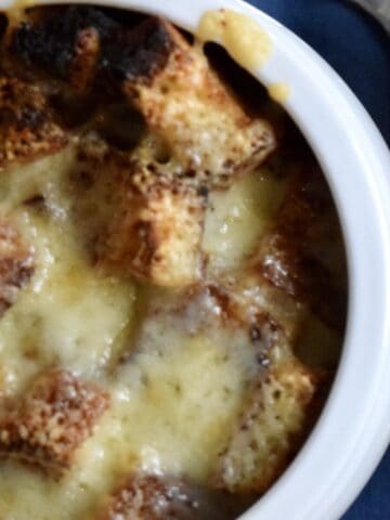 white bowl of french onion soup with croutons and melted swiss cheese