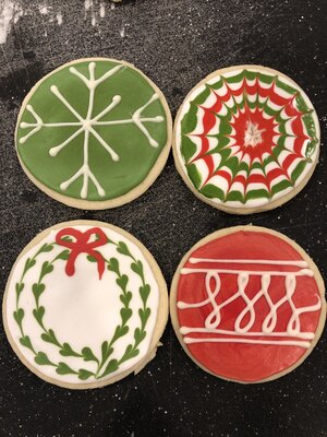 four christmas sugar cookies on a black cutting board