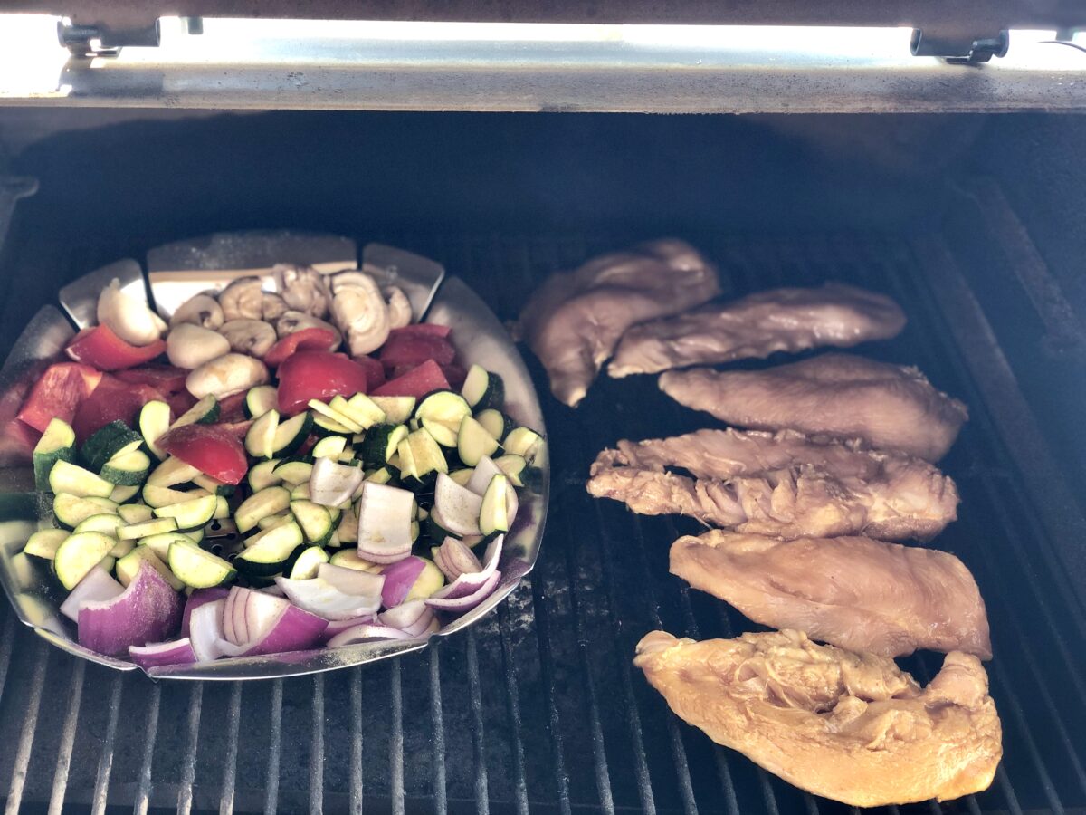 grill pan of veggies and chicken cooking on grill