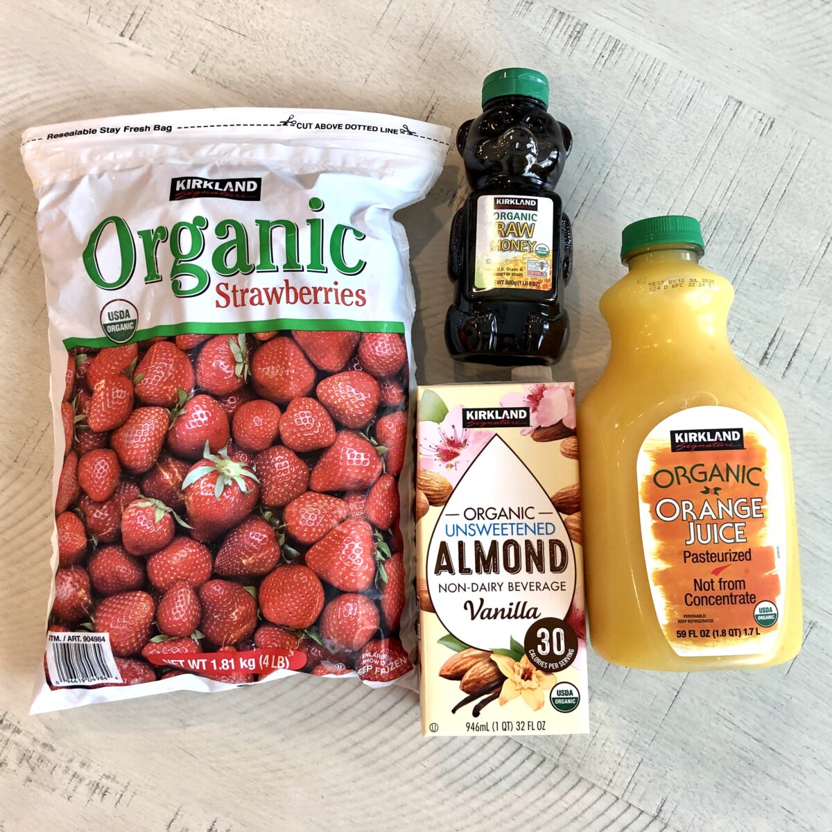 Kirkland Signature frozen strawberries, honey, almond milk, and orange juice on a table. 