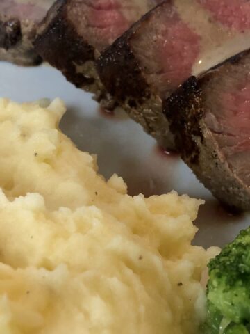 white plate of mashed potatoes, steak, and broccoli