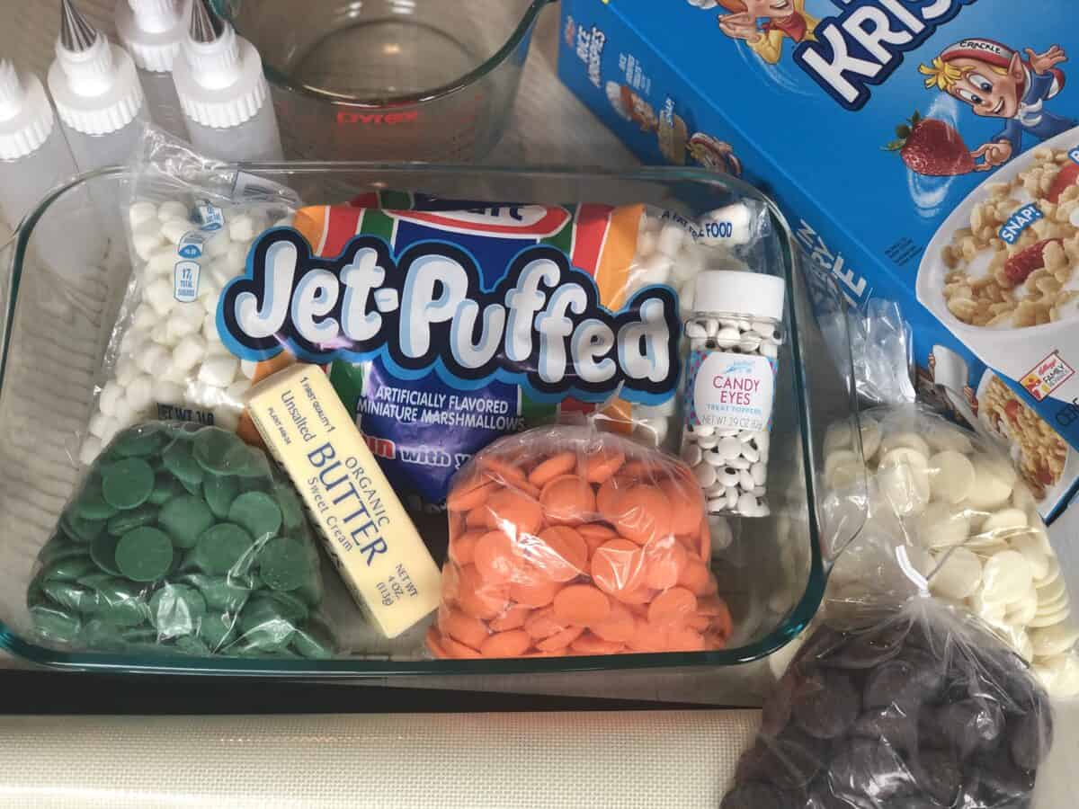 box of rice krispie cereal bag of marshmallows 4 plastic piping bottles a stick of butter bottle of candy eye sprinkles and orange green, white and brown chocolate candy melts