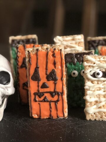 plastic skull halloween decoration and rice krispie treats decorated like a mummy frankenstein and jack-o-lantern