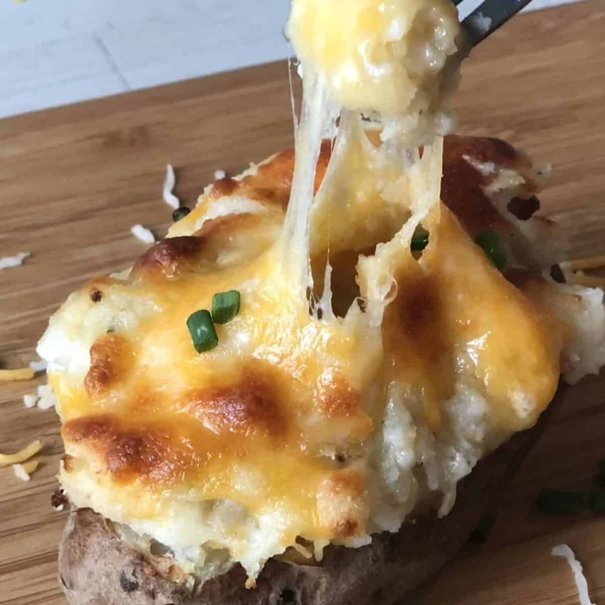 fork going into twice baked potato and cheese pulling off of fork