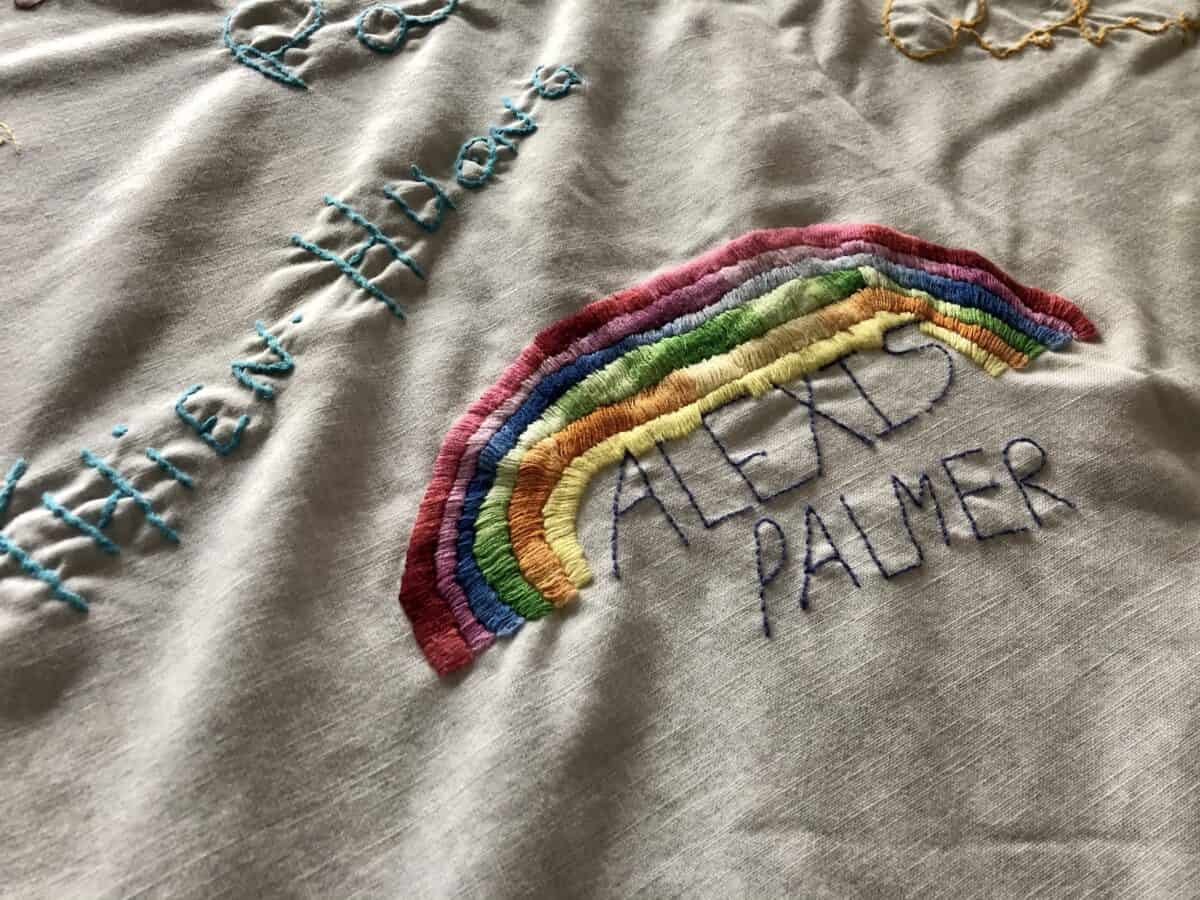 The name Alexis Palmer with a large rainbow sewn on over it