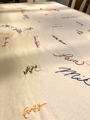 a white table cloth with several small signatures on it
