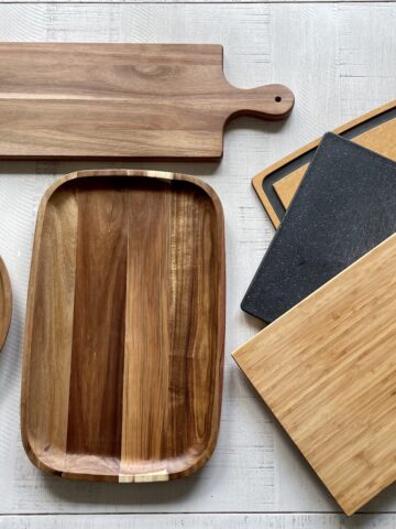 3 charcuterie boards next to 3 cutting boards on a white table