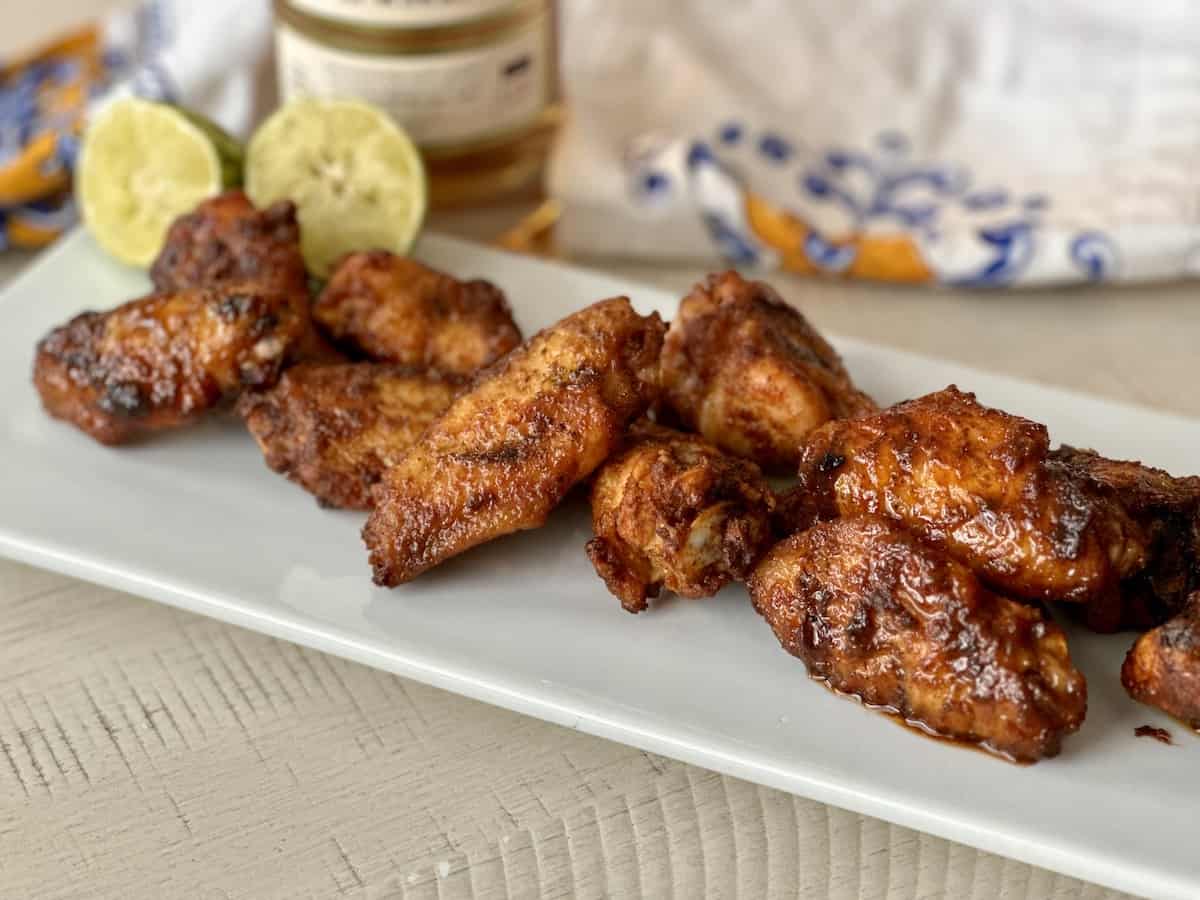 tequila lime chicken wings on a white platter with a white apron and lime