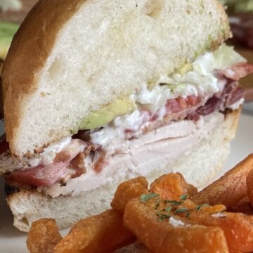 chicken Cobb sandwich on a plate with sweet potato fries