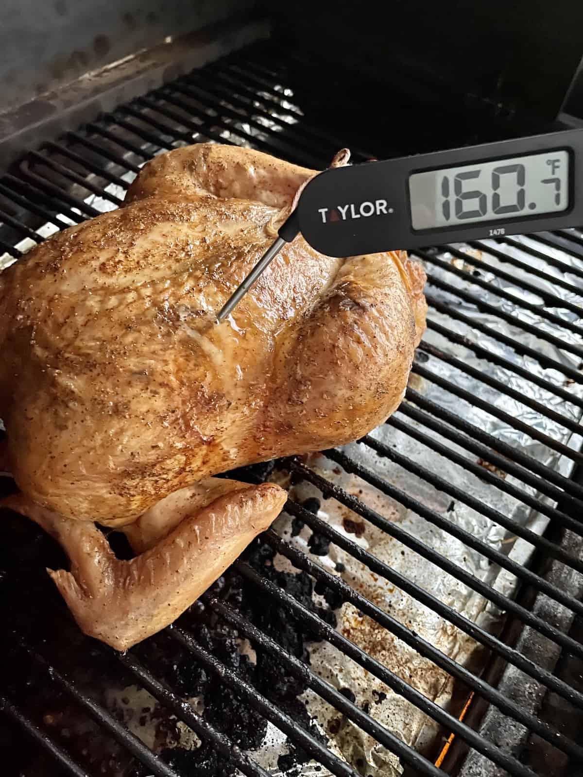 whole smoked chicken cooked on the traeger grill with a  thermometer reading 160.7 degrees fahrenheit 