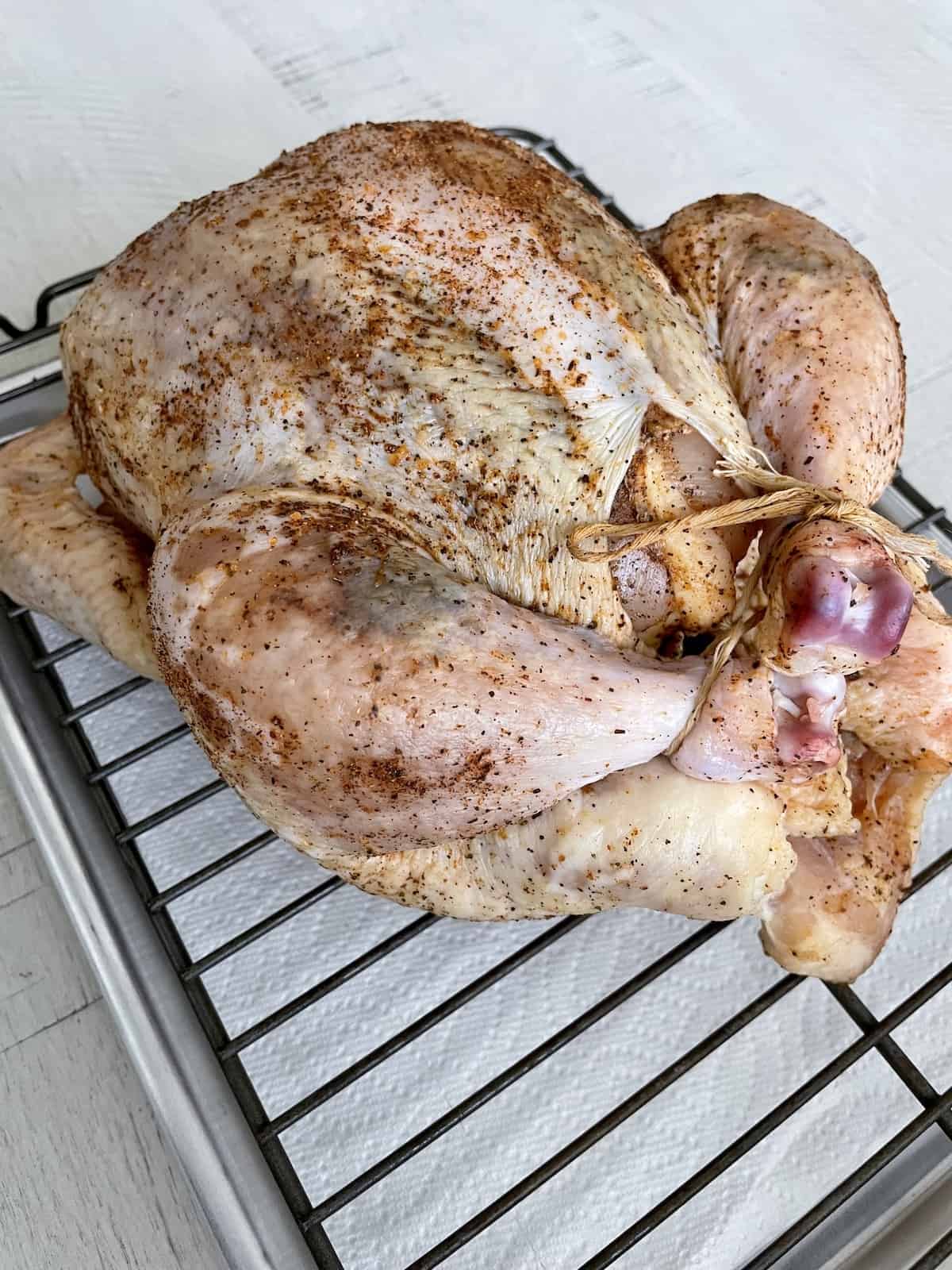 a dry brined chicken on a sheet pan with a wire rack showing the transformation of color and texture