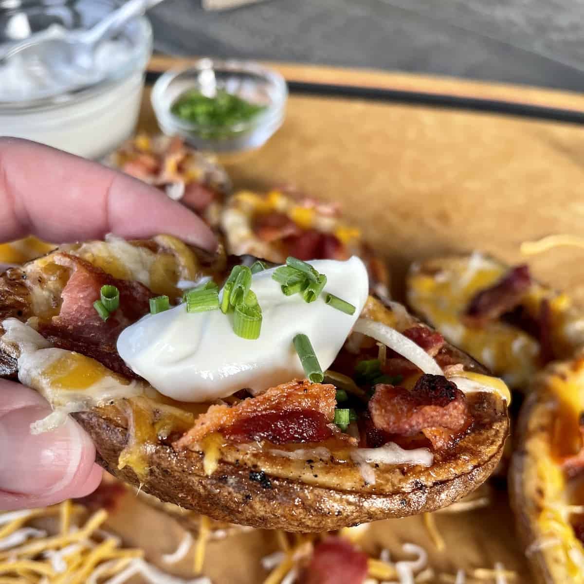 close up picture of a potato skin topped with sour cream and diced chives