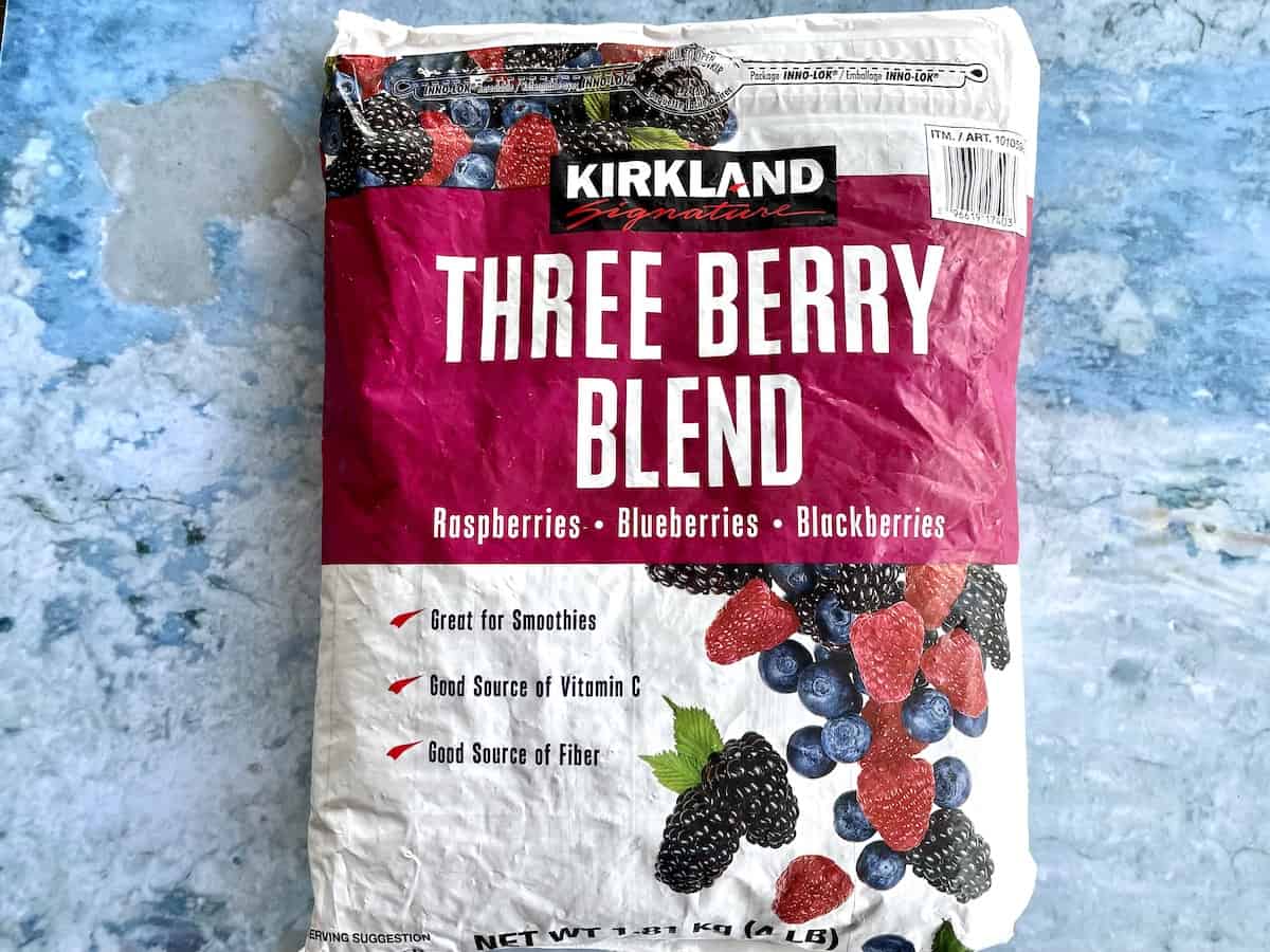 a bag of kirkland signature frozen three berry blend on top of a blue background