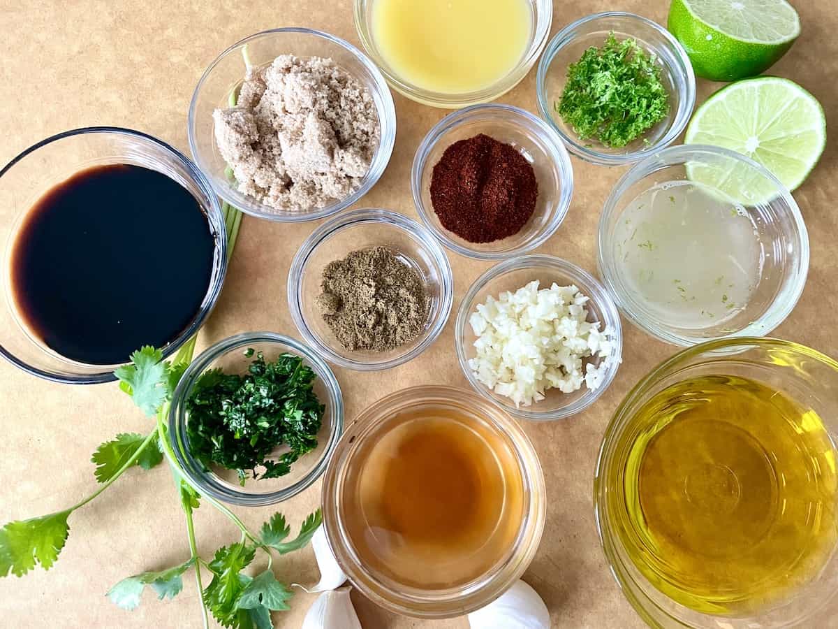 carne asada marinade ingredients in individual glass bowls set up on a brown cutting board prepared for use