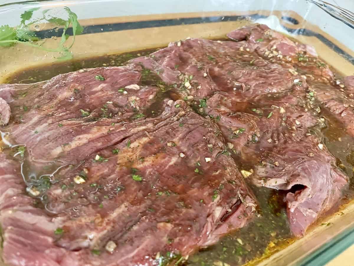 glass baking dish with flap steak marinating in carne asada marinade