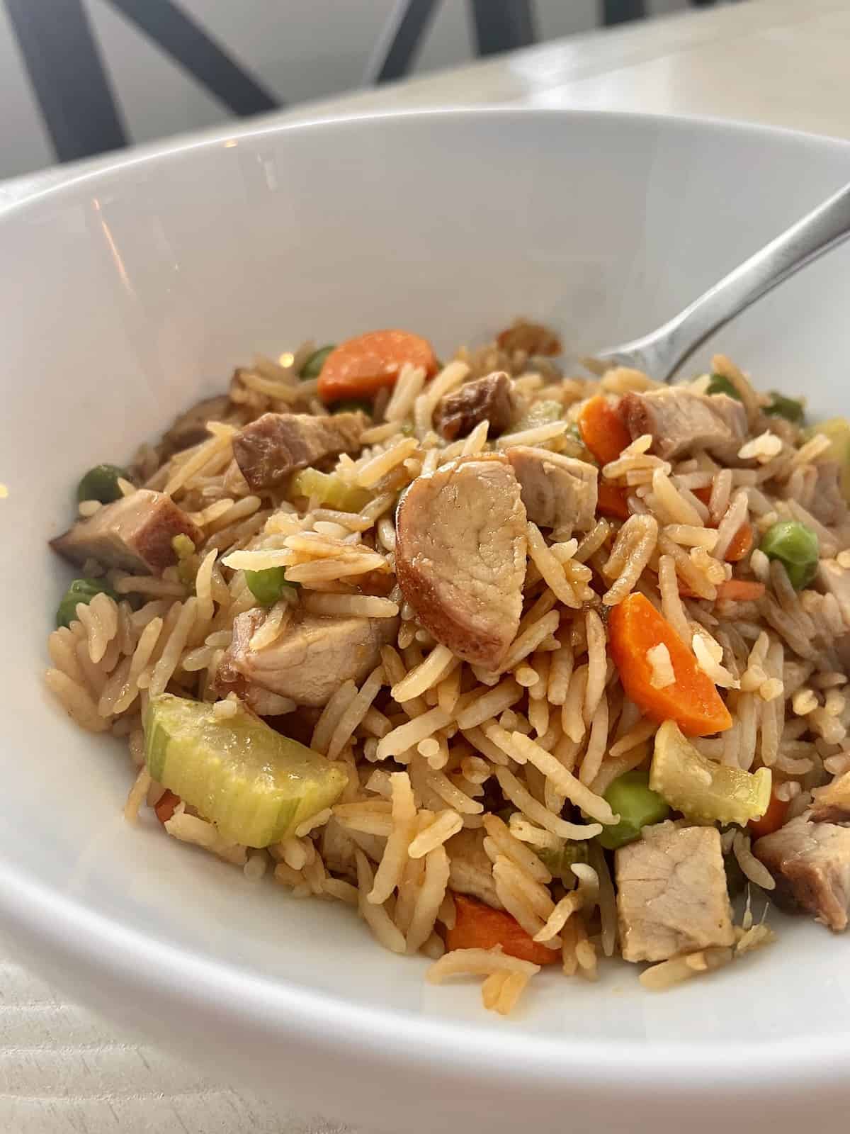 a white bowl of fried rice from the leftover traeger pork tenderloin with rice carrots peas and celery