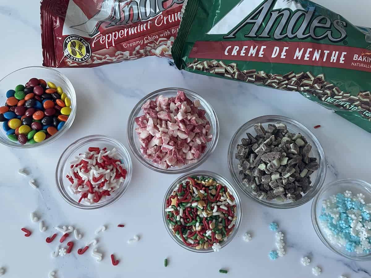 assorted toppings and sprinkles including mini m&ms christmas sprinkles candy canes sprinkles and snowflake sprinkles