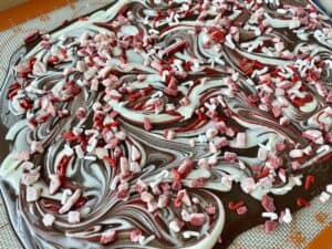 a whole slab of chocolate peppermint bark showing dark chocolate white chocolate and red chocolate swirls with peppermint candy pieces and sprinkles