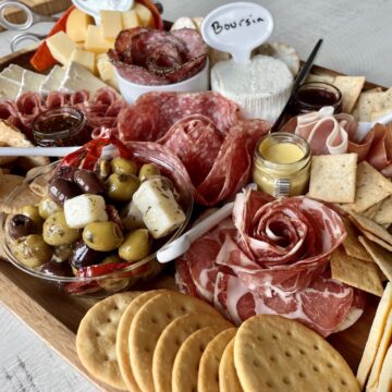 charcuterie board with various meats cheeses olives spreads and crackers