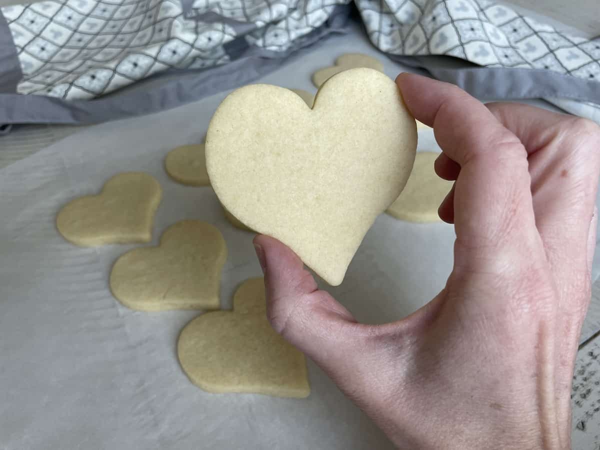 Alexis' hand holding a baked heart shaped sugar cookie