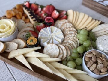 cheese board including various sliced cheeses fruit crackers and spreads to illustrate a cheese board vs charcuterie board