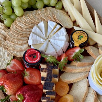 cheese surrounded by spreads crackers and grapes