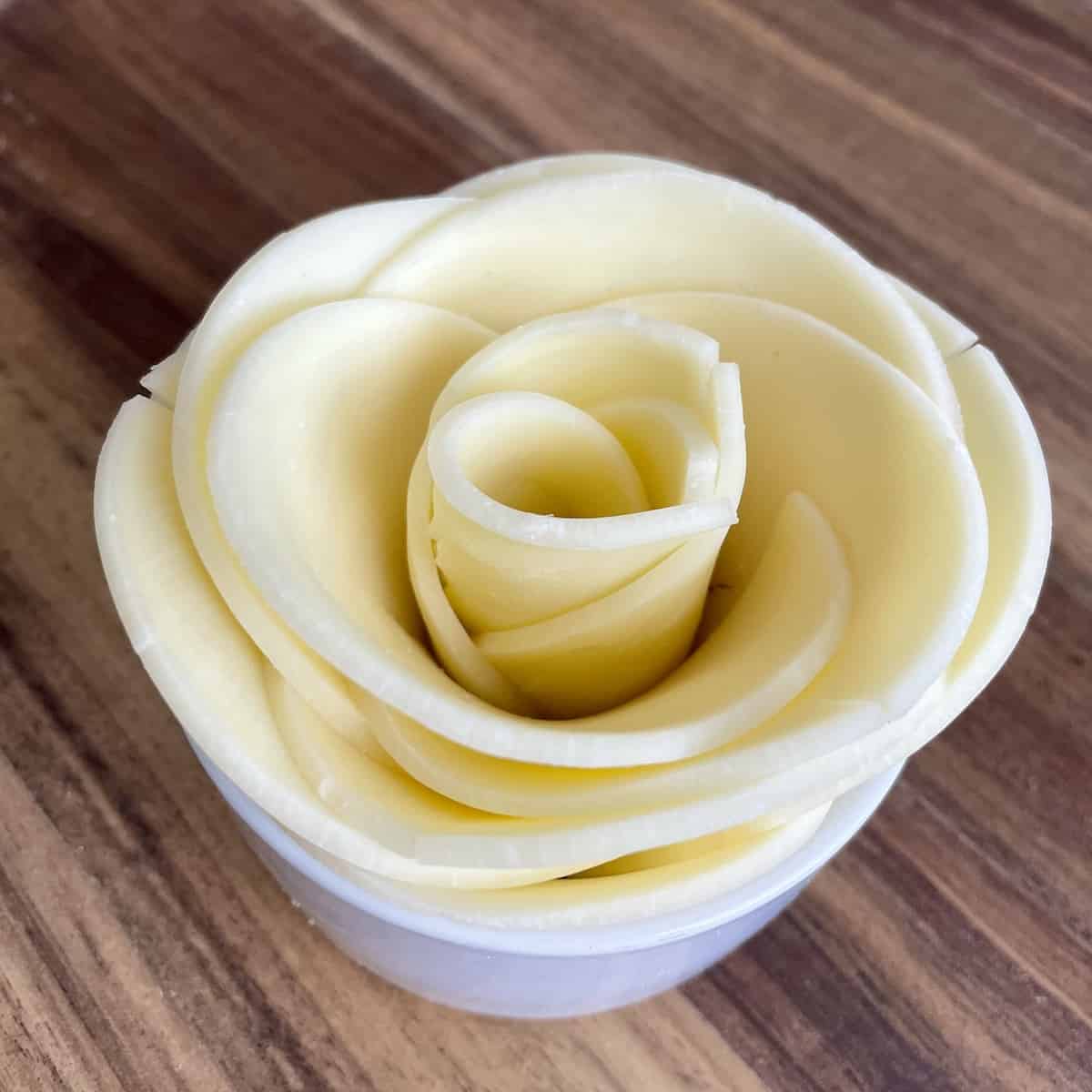 sliced provolone cheese layered in a small white bowl to look like a rose