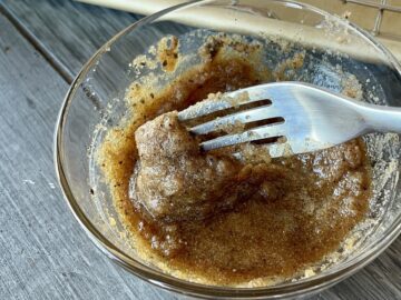 brown sugar and bourbon mixture in a glass bowl stirred with a fork ton a wood table