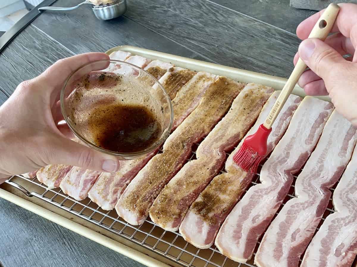 brown sugar and bourbon mixture being brushed on to the thick cut bacon slices