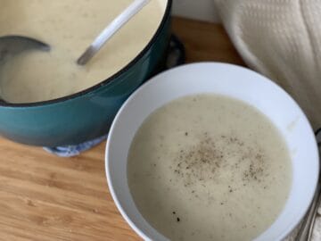 3-ingredient potato soup served in a white bowlines to teal dutch oven