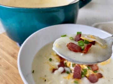 3 ingredient potato soup on a spoon with bacon cheese and chives