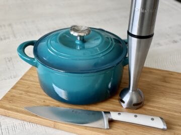 teal dutch oven on a wood cutting board knife and immersion blender