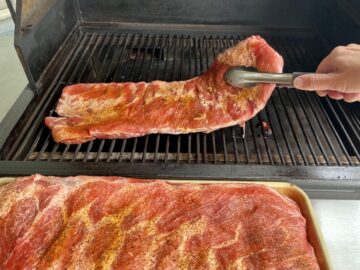 placing a rack of seasoned ribs on to a Traeger Grill