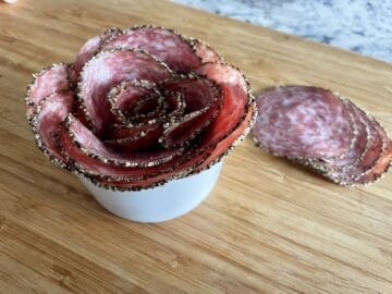 salami rose in a small white bowl on a wood cutting board