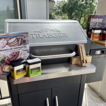 Traeger smoker with Traeger rubs a wood cutting board meater plus thermometer and cookbooks on top