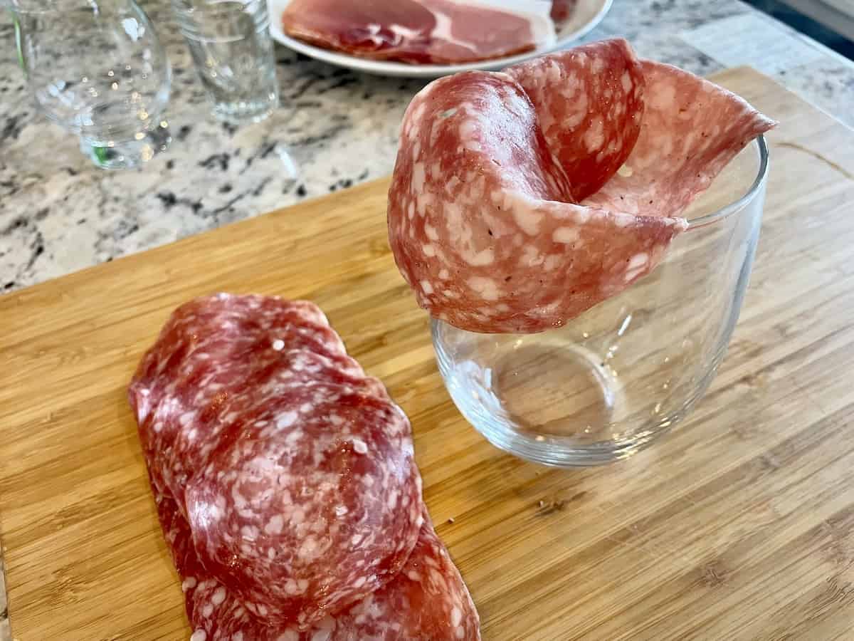 layered salami on a stemless wine glass with more salami circles next to it