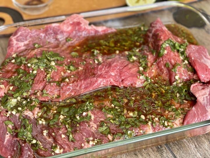 two large pieces of skirt steak marinating in a large glass baking dish