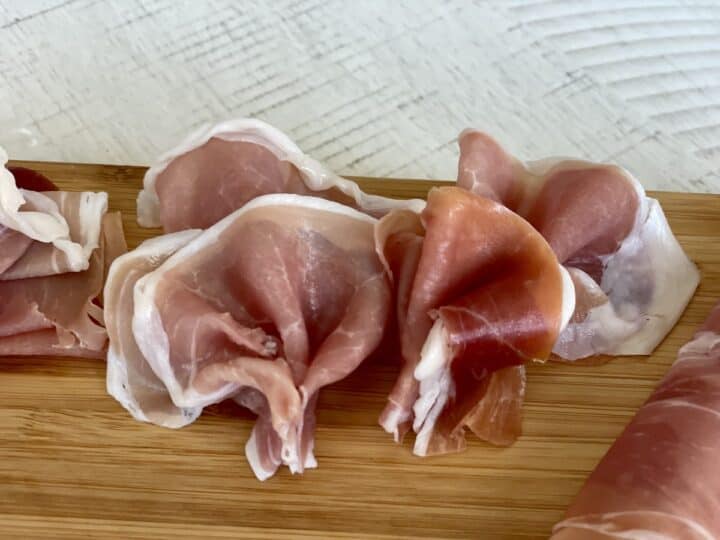 4 prosciutto fans on a wood cutting board