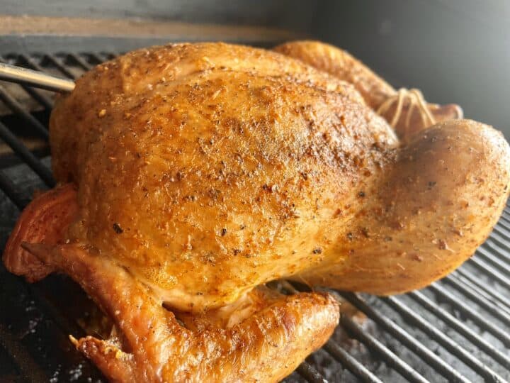 whole chicken cooking on the grates of a traeger grill