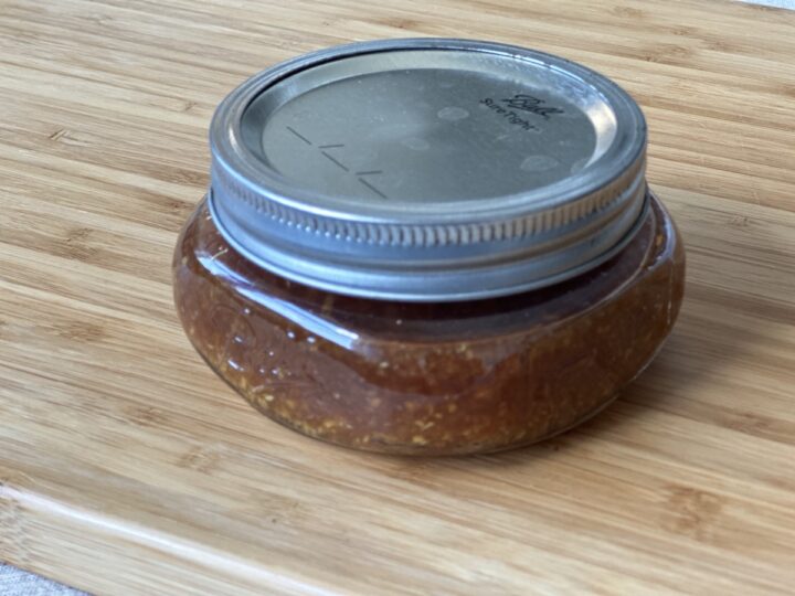 small mason jar filled with dipping sauce on a wood cutting board