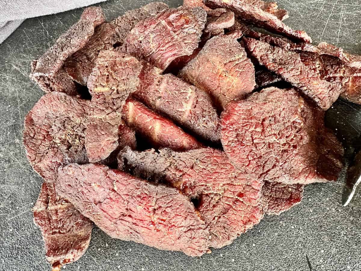 homemade beef jerky slices on black cutting board