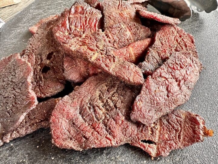 smoked beef jerky on a black cutting board close up