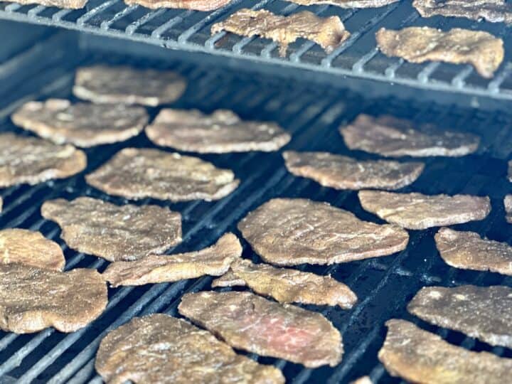 marinated beef slices spread out in a single layer on Traeger grill grates