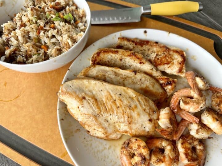 cooked Traeger hibachi chicken and shrimp on white plate white bowl of fried rice on wood cutting board chefs knife