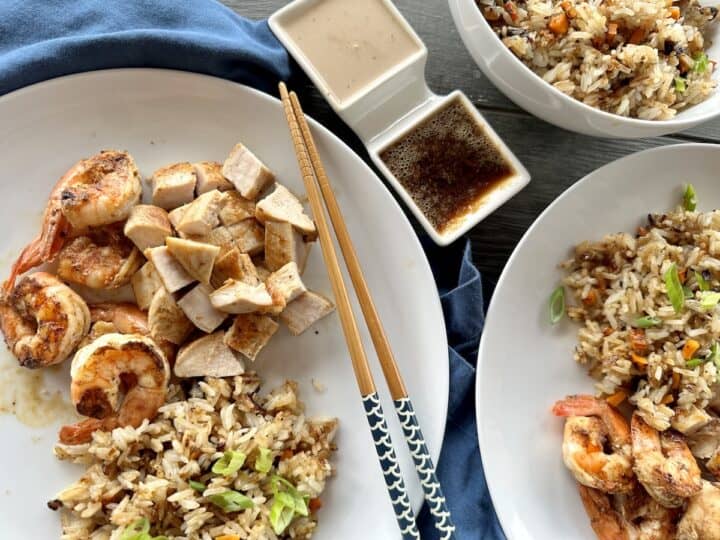 white plates of hibachi chicken and shrimp dipping sauces chopsticks and blue napkins