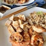 white plate with cooking hibachi chicken shrimp and friend rice Japanese chopsticks ginger dipping sauce