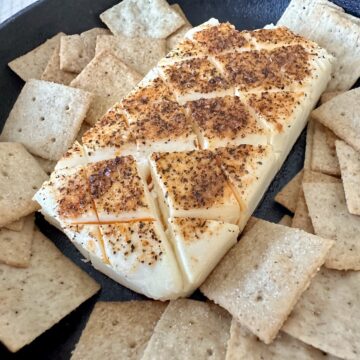 smoked cream cheese in cast iron skillet with square crackers around it