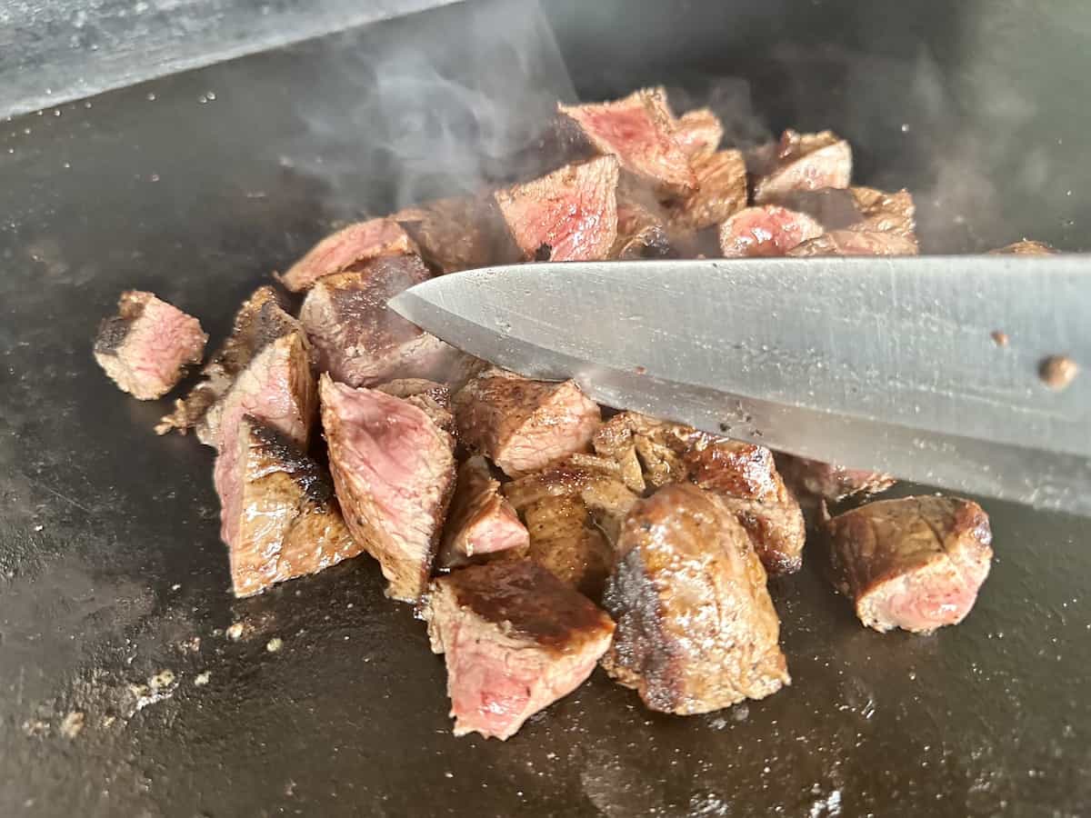 chefs knife cutting steak on traeger flat rock