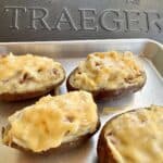 four twice smoked potatoes on sheet pan in front of Traeger Grill