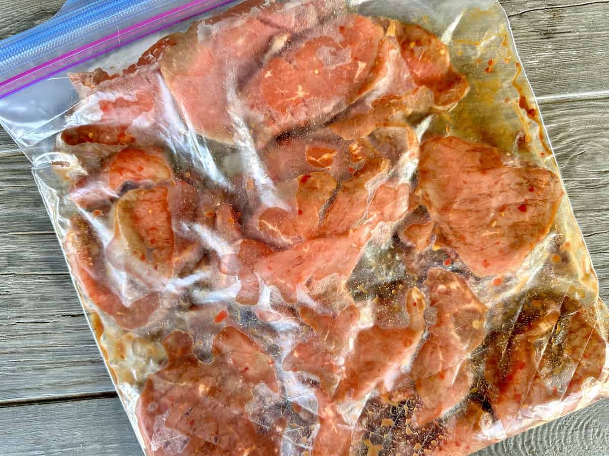 sliced beef marinating in zip top bag